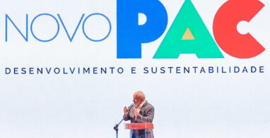 Foto do presidente Lula discursando, ao fundo há escrito "novo PAC - desenvolvimento sustentável"